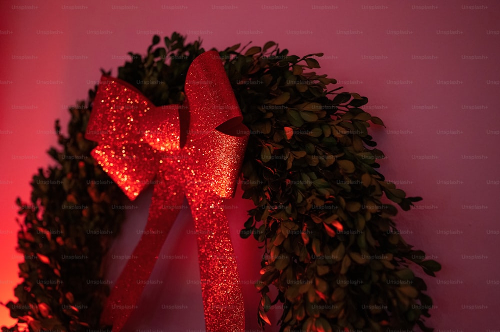 a lighted wreath with a red bow hanging on a wall