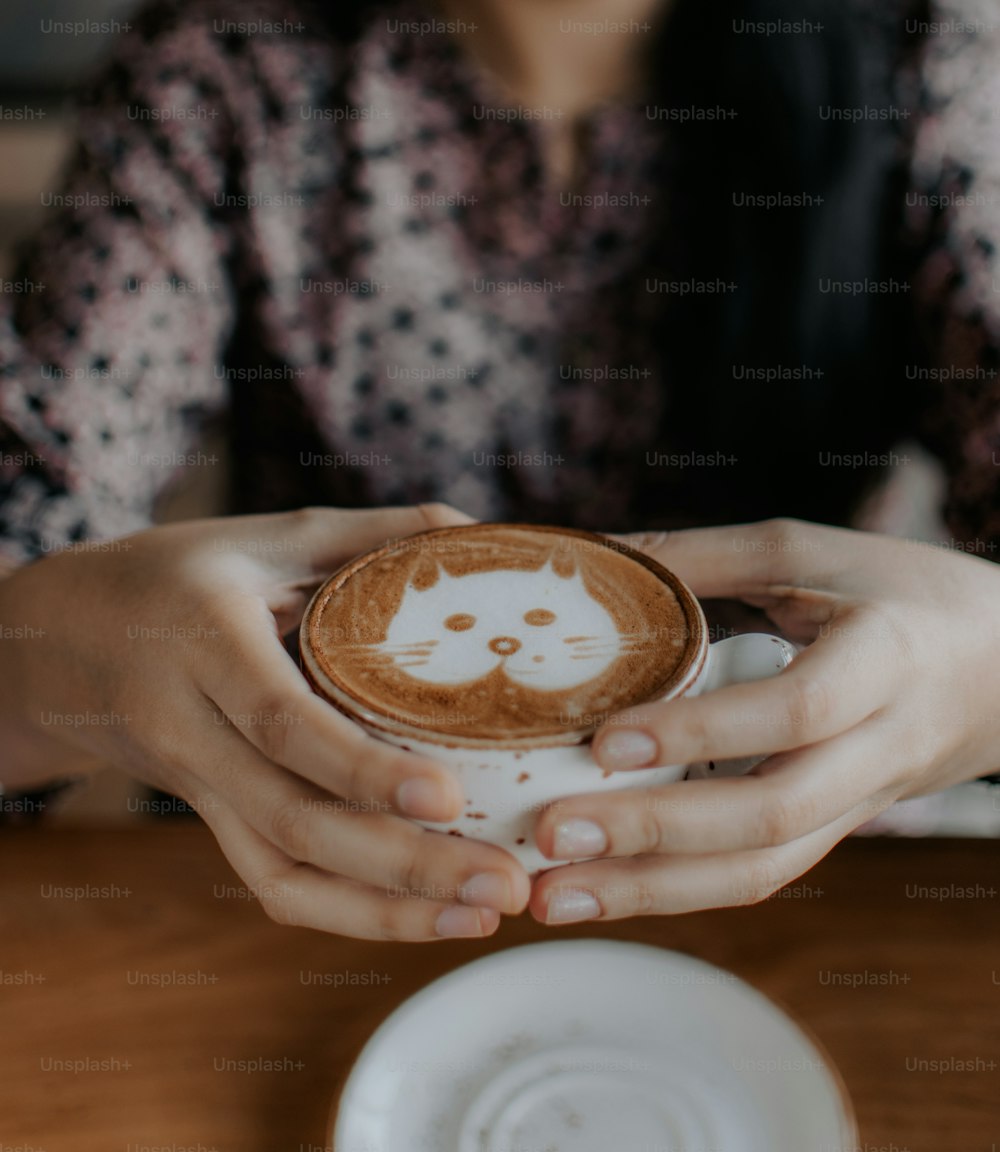 a person holding a cup with a cat drawn on it