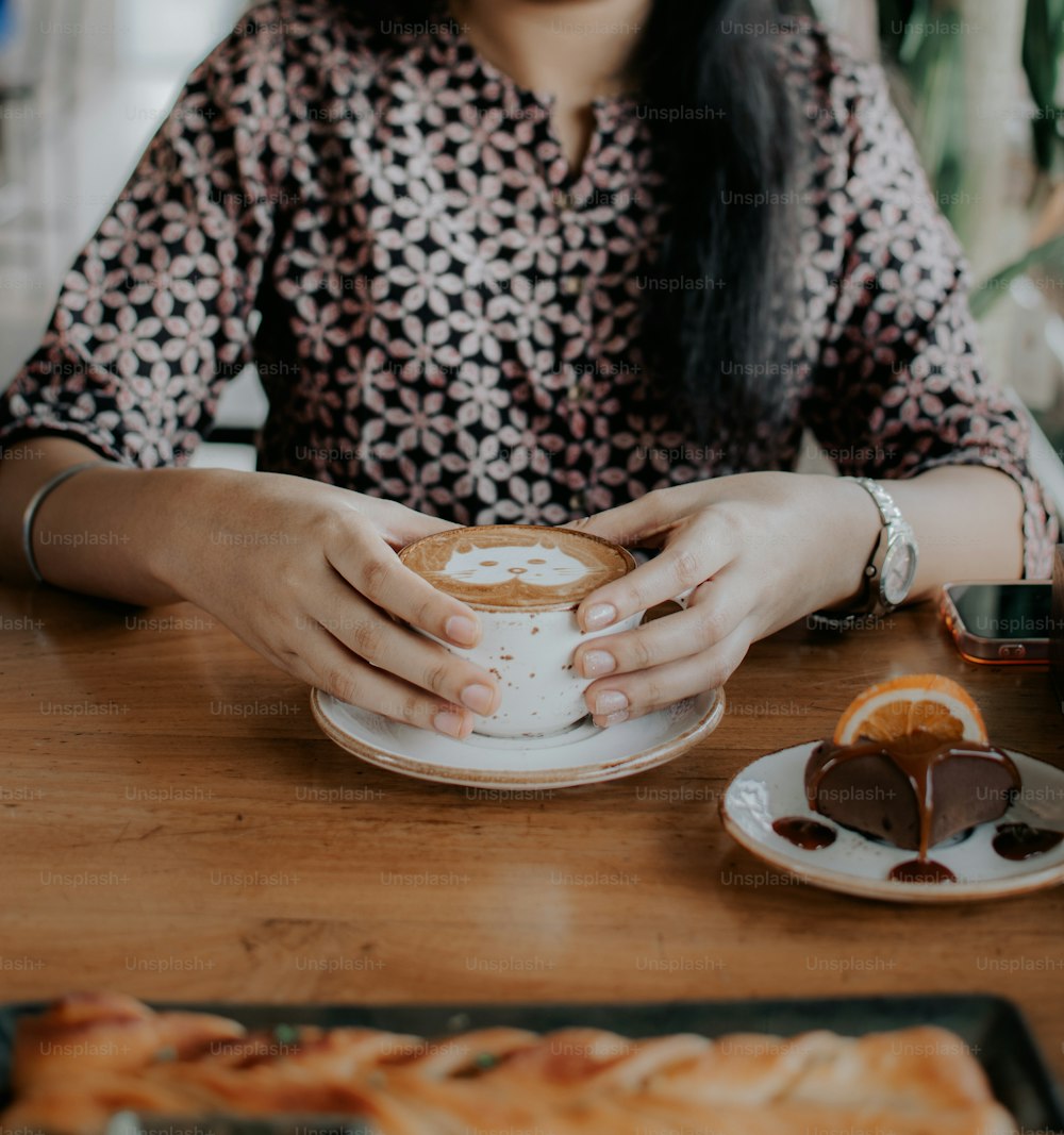 uma mulher sentada em uma mesa segurando uma xícara de café