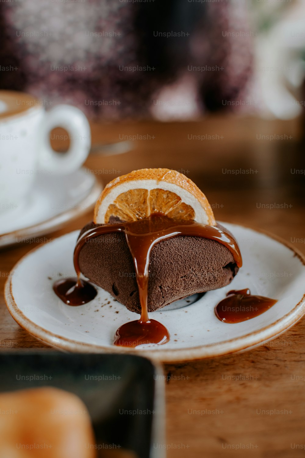 a piece of chocolate cake on a plate with a slice of orange