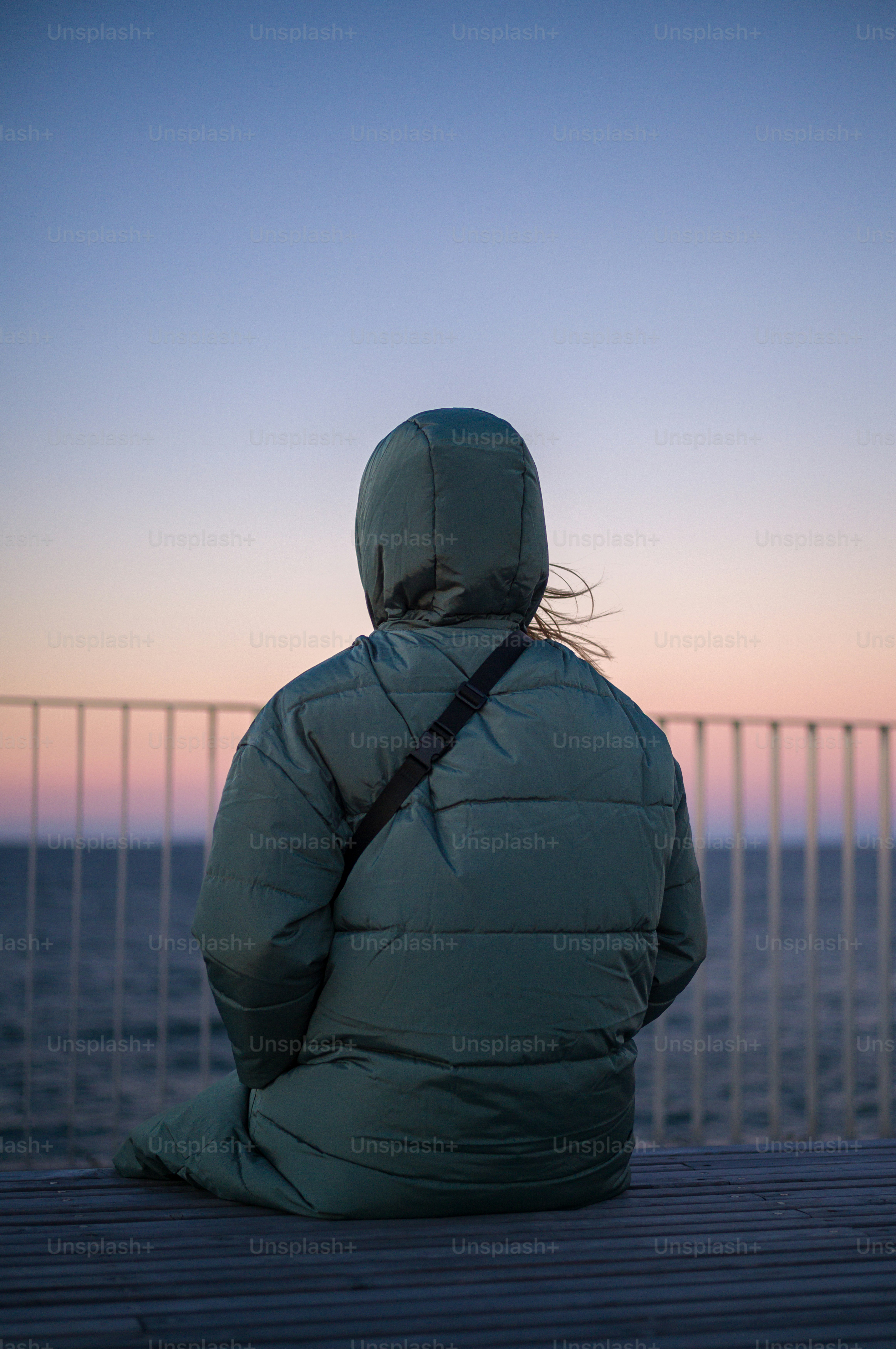 Eine Person, die auf einer Bank sitzt und auf den Ozean blickt