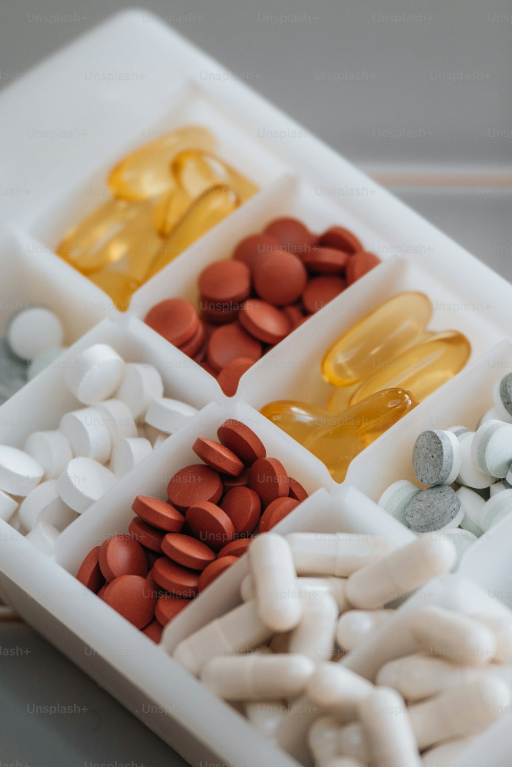 ein weißes Tablett gefüllt mit Pillen und Vitaminen