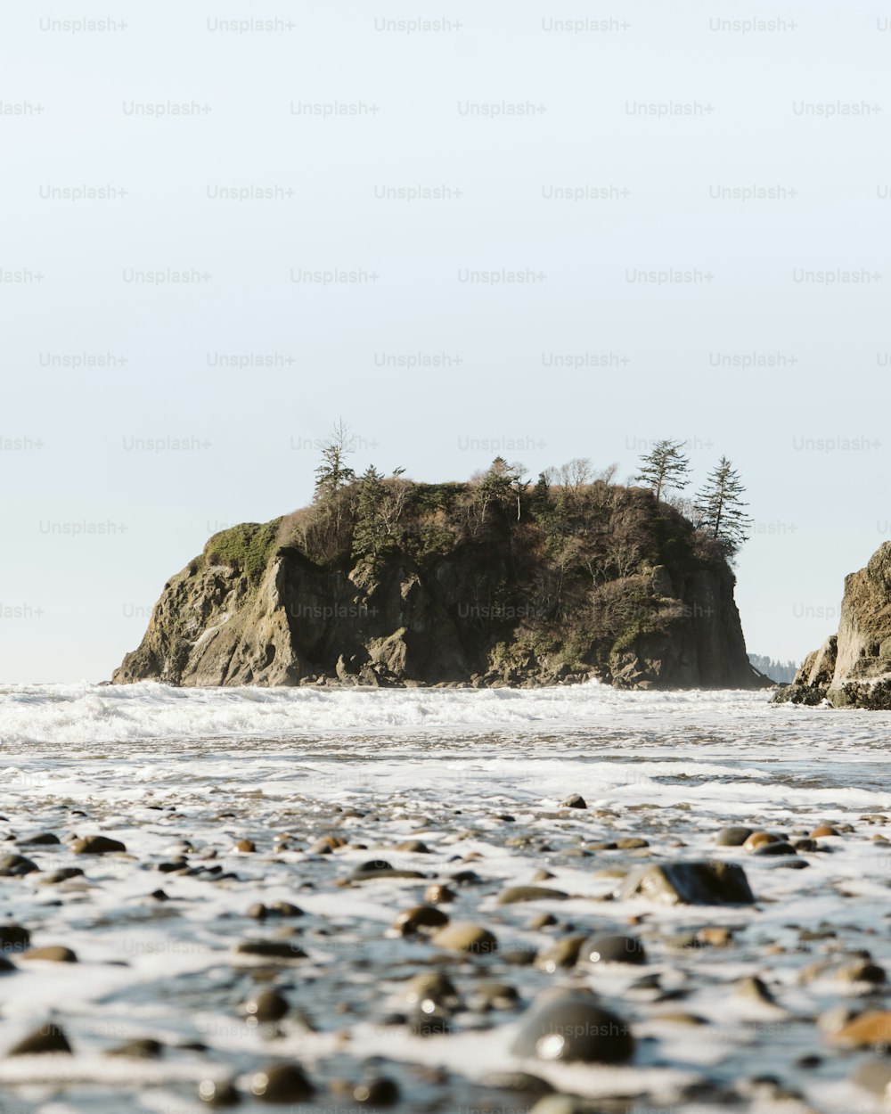 遠くに小さな島がある岩だらけのビーチ