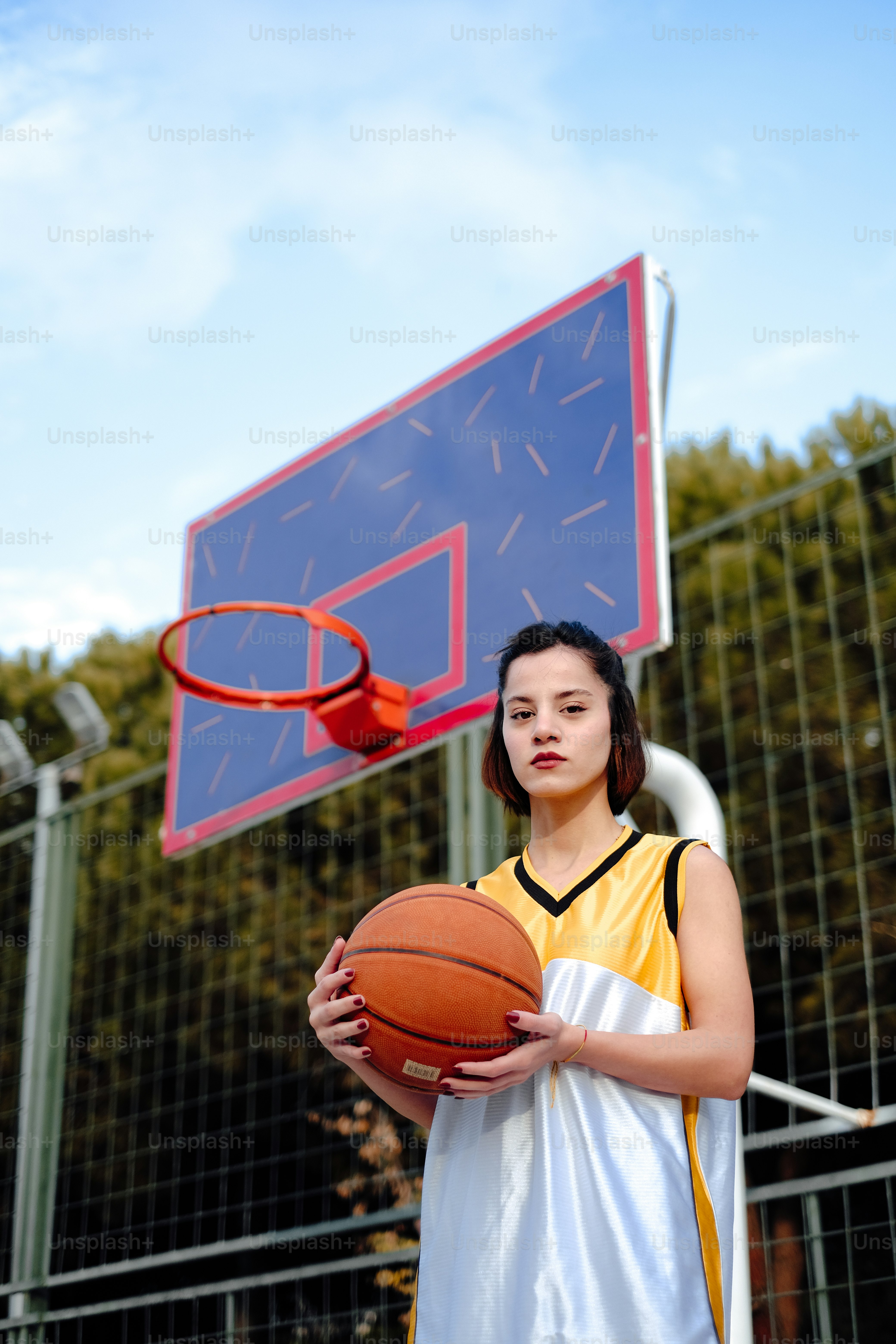 a girl holding a basketball in front of a basketball hoop