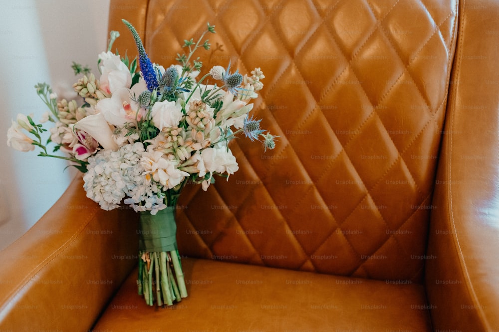 a bouquet of flowers sitting on a leather chair