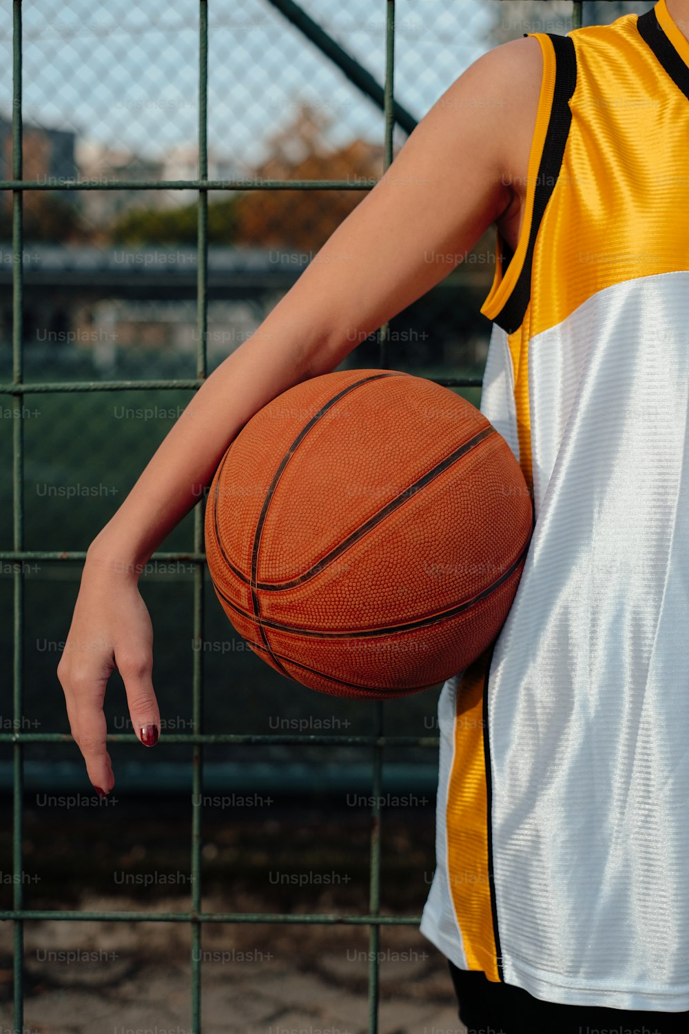 a person holding a basketball in front of a fence