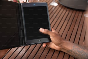 a person holding a tablet on a wooden table