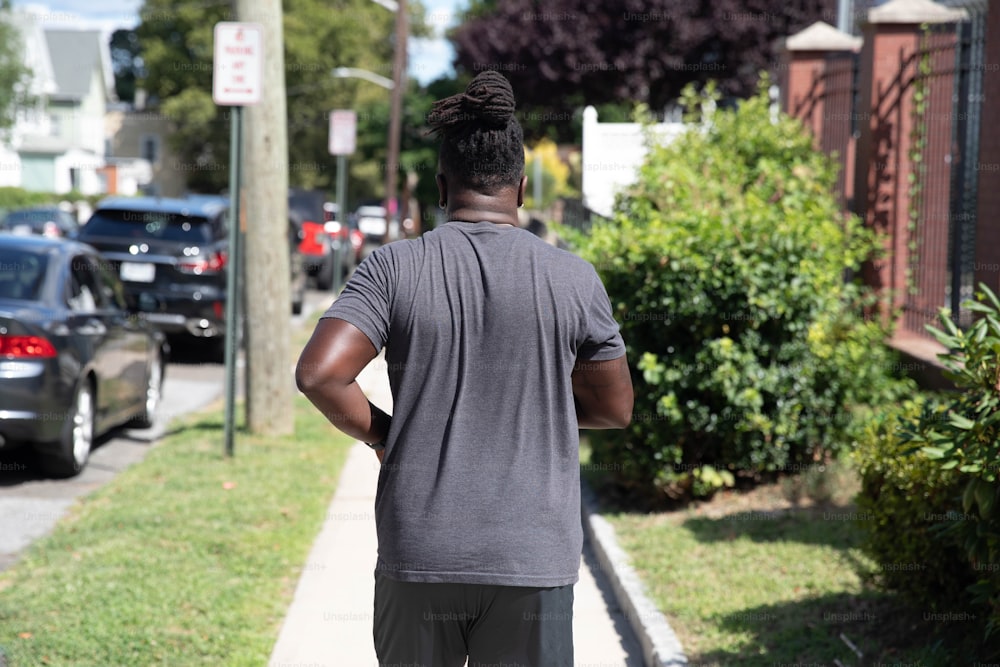 a man walking down a sidewalk with his back to the camera