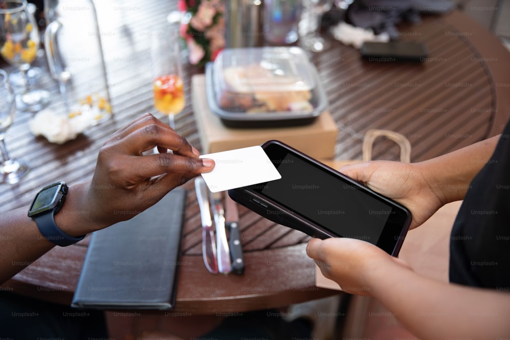 a person holding a smart phone with a business card in their hand