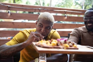 two men sitting at a table with a tray of food