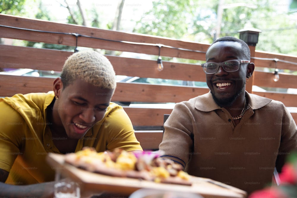 a couple of men sitting at a table with a plate of food