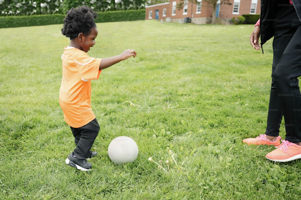 Un petit garçon donnant un coup de pied dans un ballon de football dans un champ