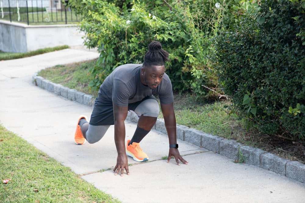 a man in grey shirt and orange shoes doing a push up