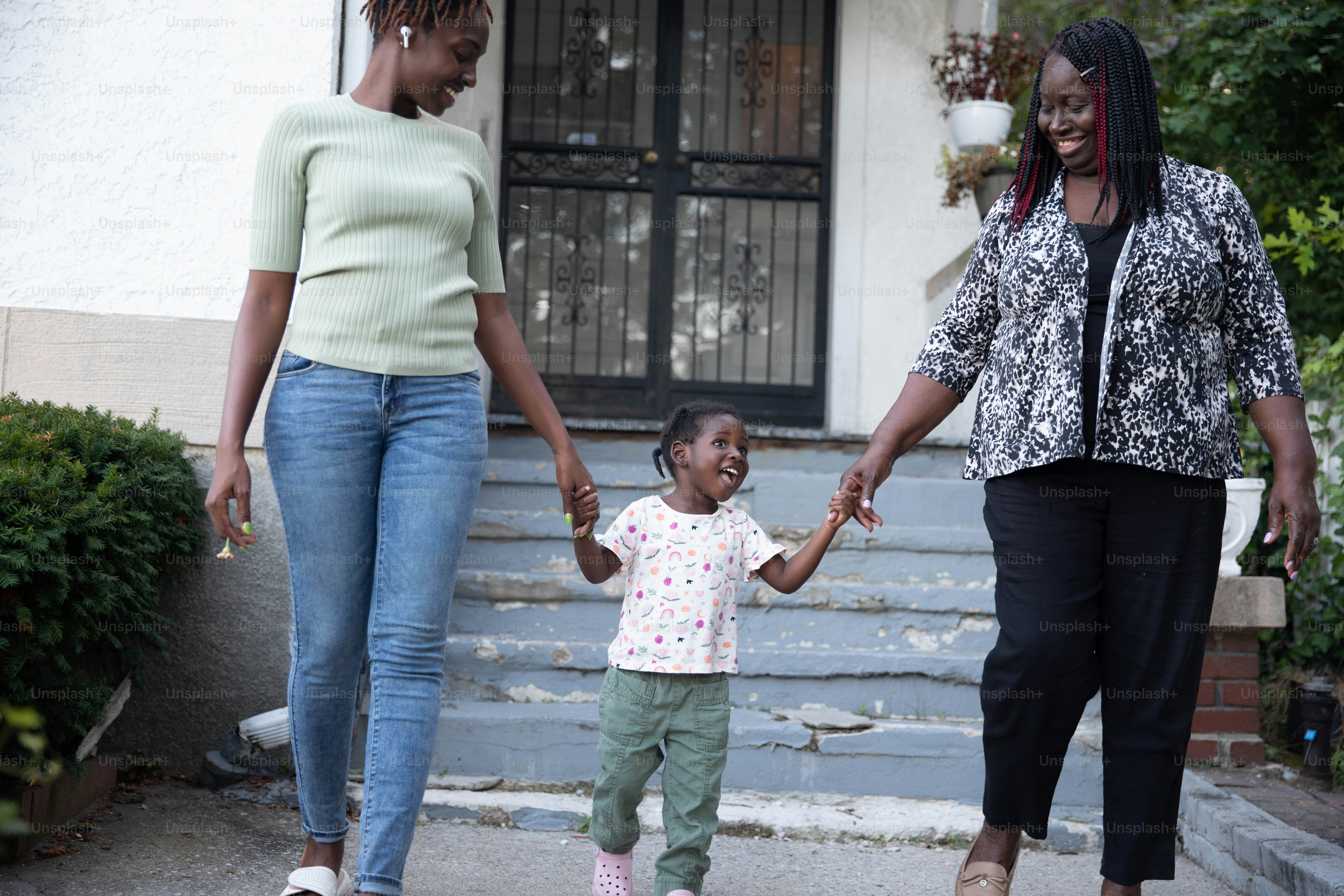 a woman holding the hand of a little girl