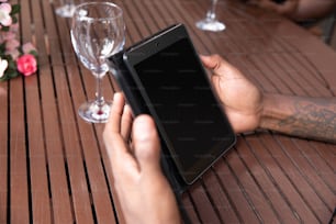 una persona che tiene un telefono cellulare sopra un tavolo di legno
