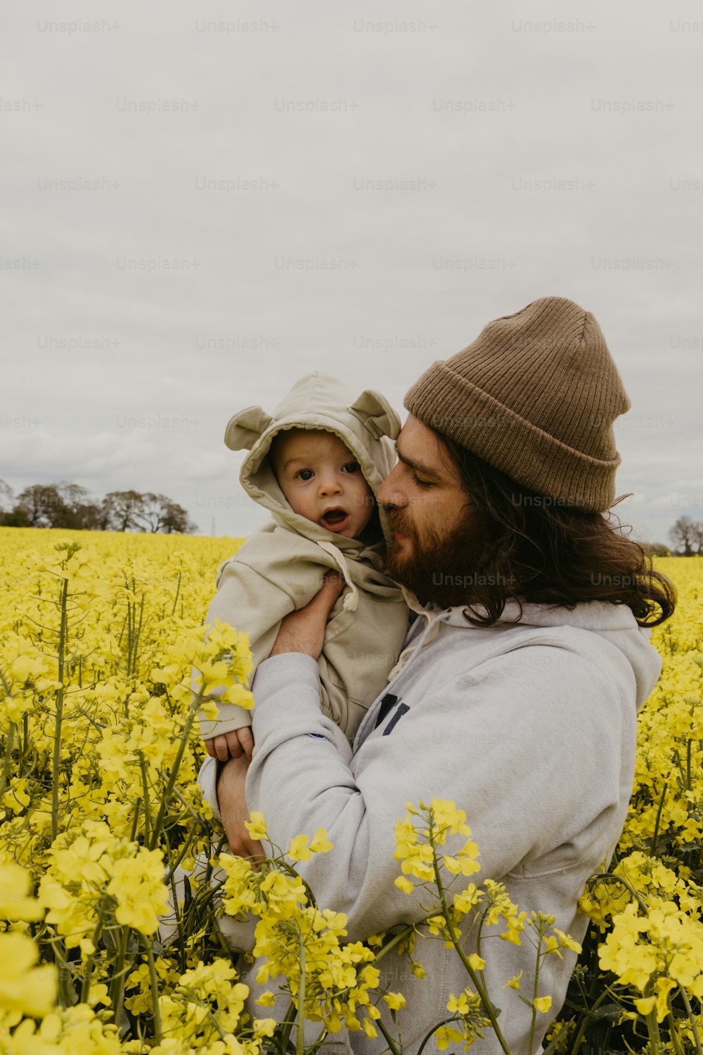um homem segurando um bebê em um campo de flores amarelas
