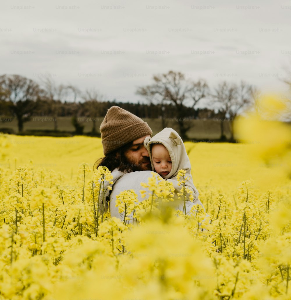 um homem segurando uma criança em um campo de flores amarelas