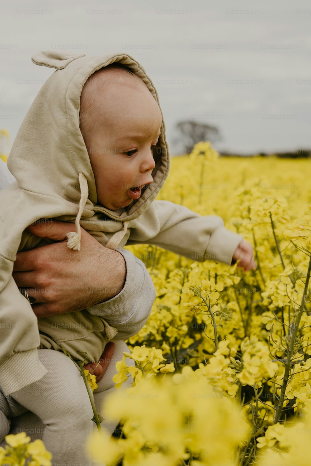 a man holding a baby in a field of yellow flowers