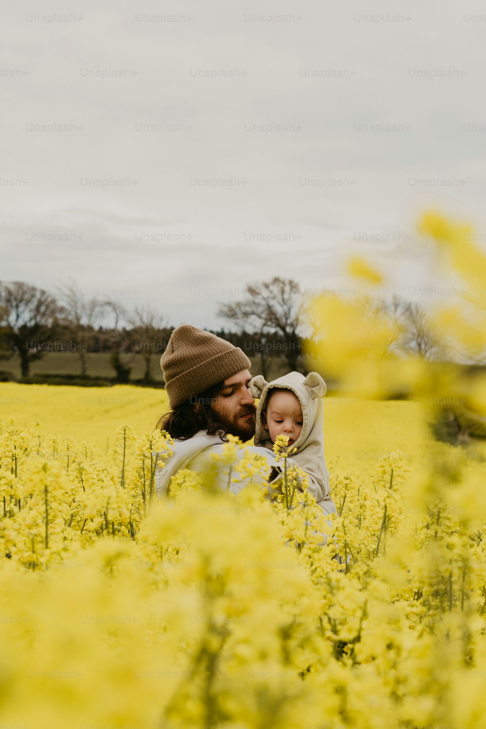 Ein Mann, der ein Baby in einem Feld mit gelben Blumen hält