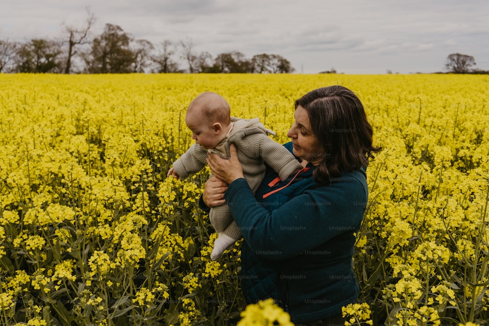 a woman holding a baby in a field of yellow flowers