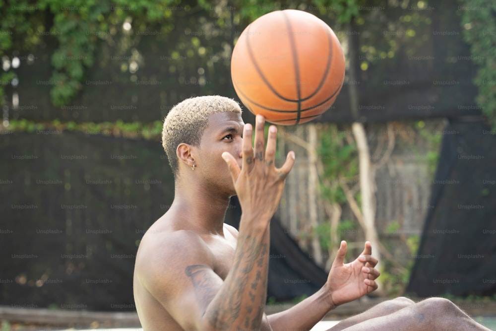 Ein Mann ohne Hemd, der sich einen Basketball vor das Gesicht hält