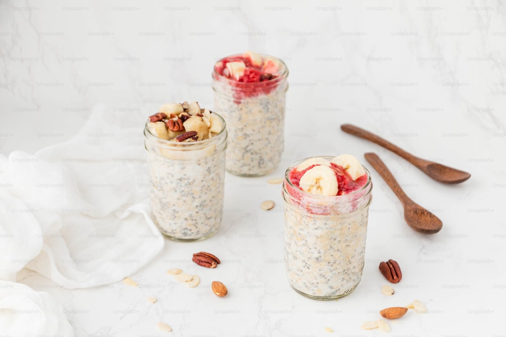 Tre barattoli pieni di farina d'avena, noci e frutta