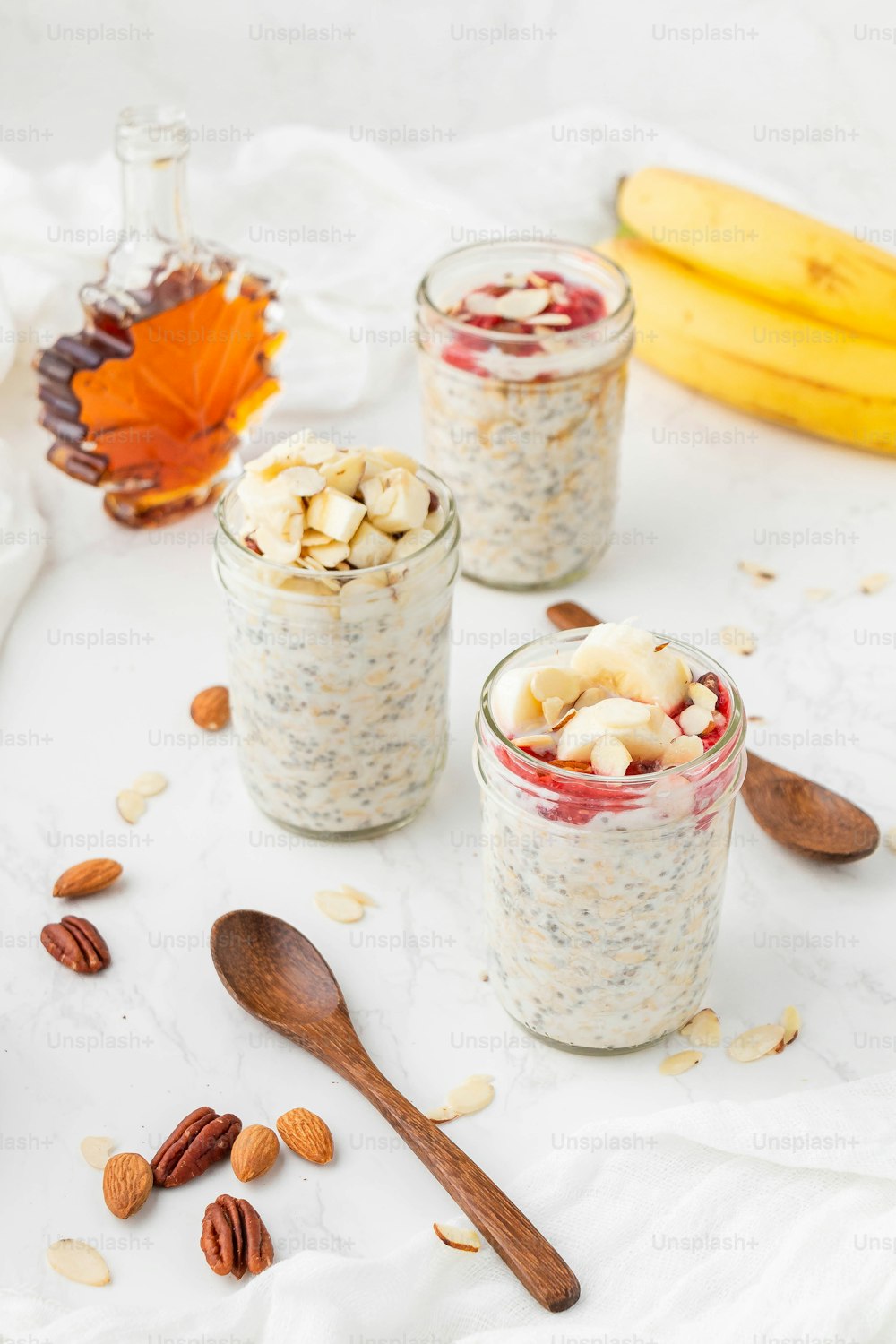 three jars filled with oatmeal and nuts on a table