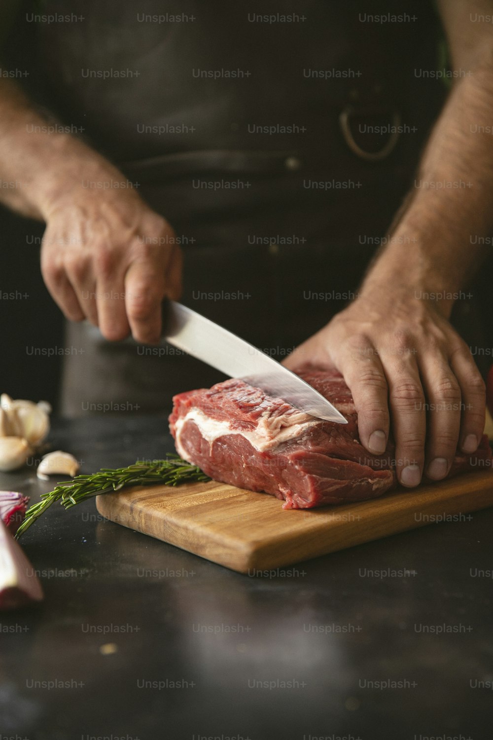 a man cutting up a piece of meat on top of a wooden cutting board