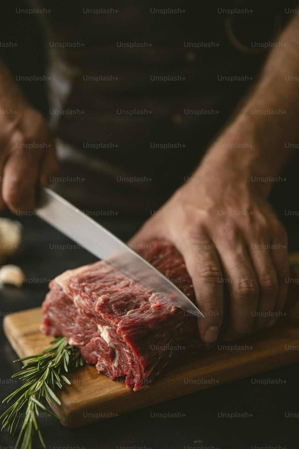 eine Person, die ein Stück Fleisch auf einem Schneidebrett zerschneidet