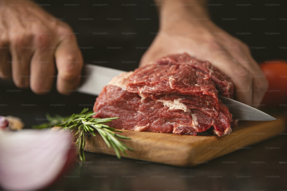a person cutting meat with a knife on a cutting board