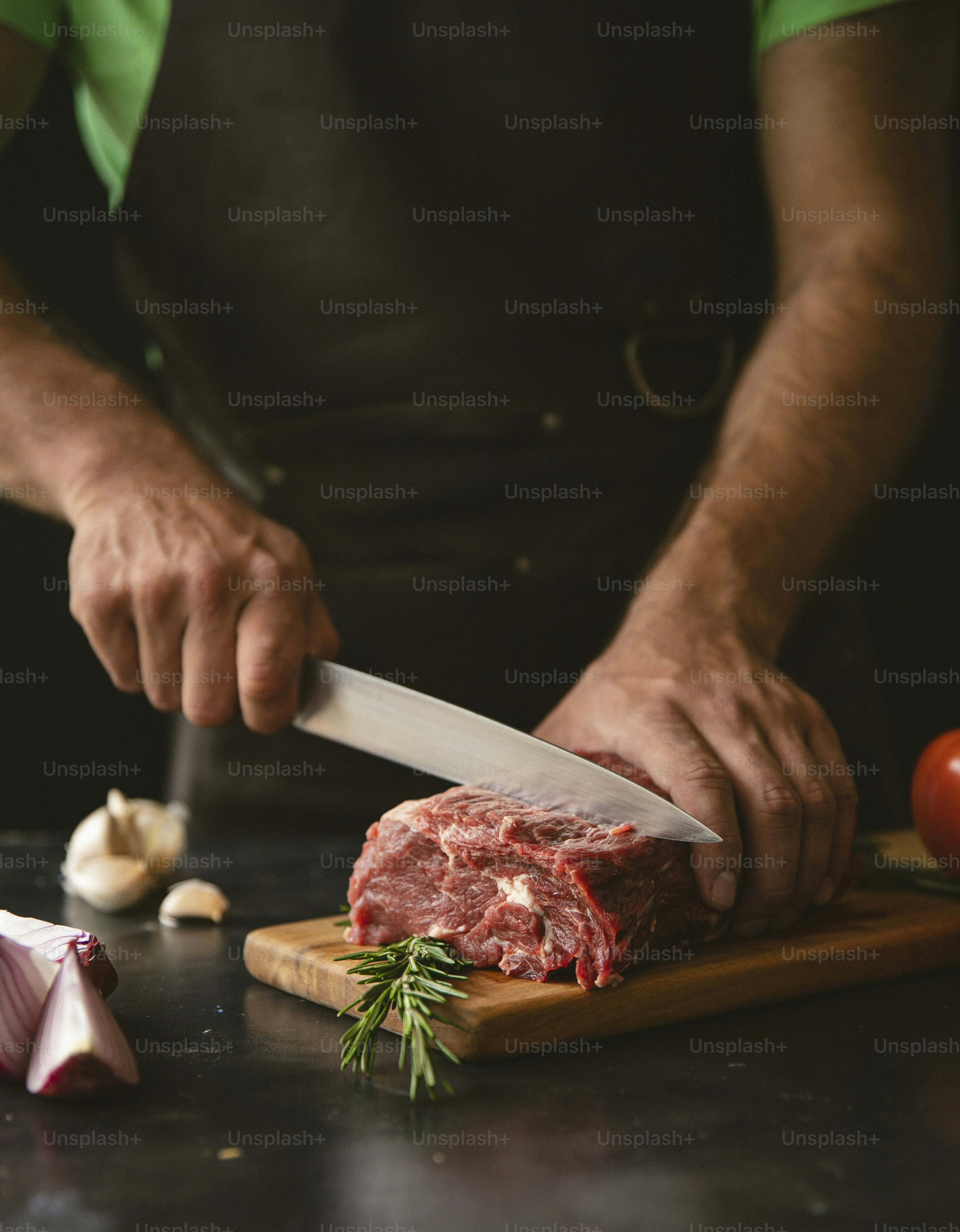 a man cutting up a piece of meat on top of a wooden cutting board