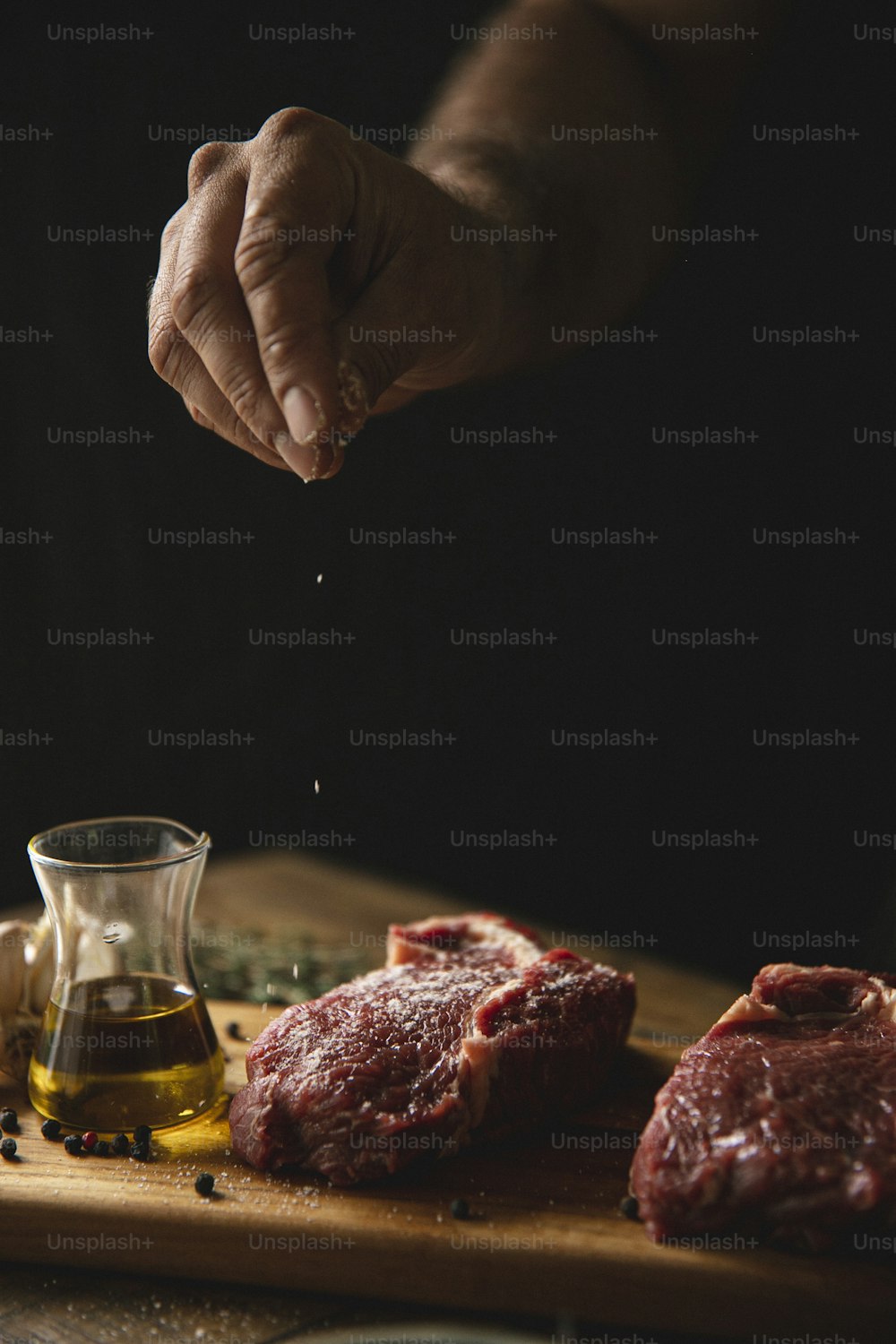 a person is sprinkling seasoning on raw meat