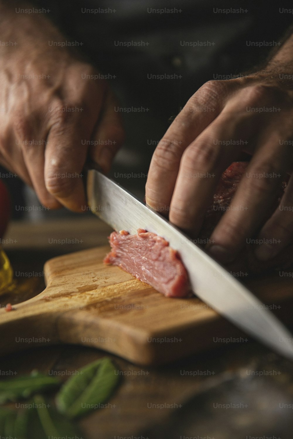 男がまな板で肉片を切っている