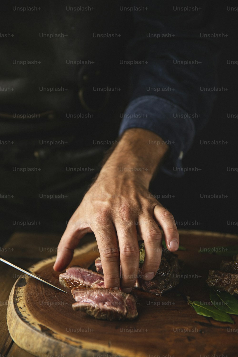 a person cutting up a piece of meat on top of a wooden cutting board