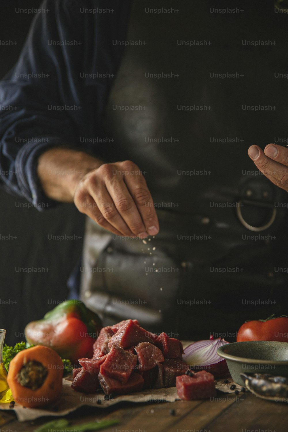 Ein Koch streut Gewürze auf ein Stück Fleisch