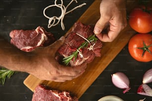 a person holding a piece of meat on a cutting board
