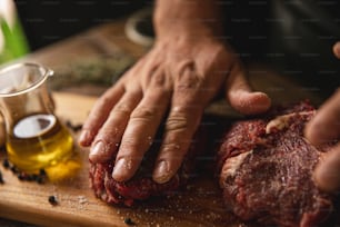 una persona sosteniendo un trozo de carne en una tabla de cortar