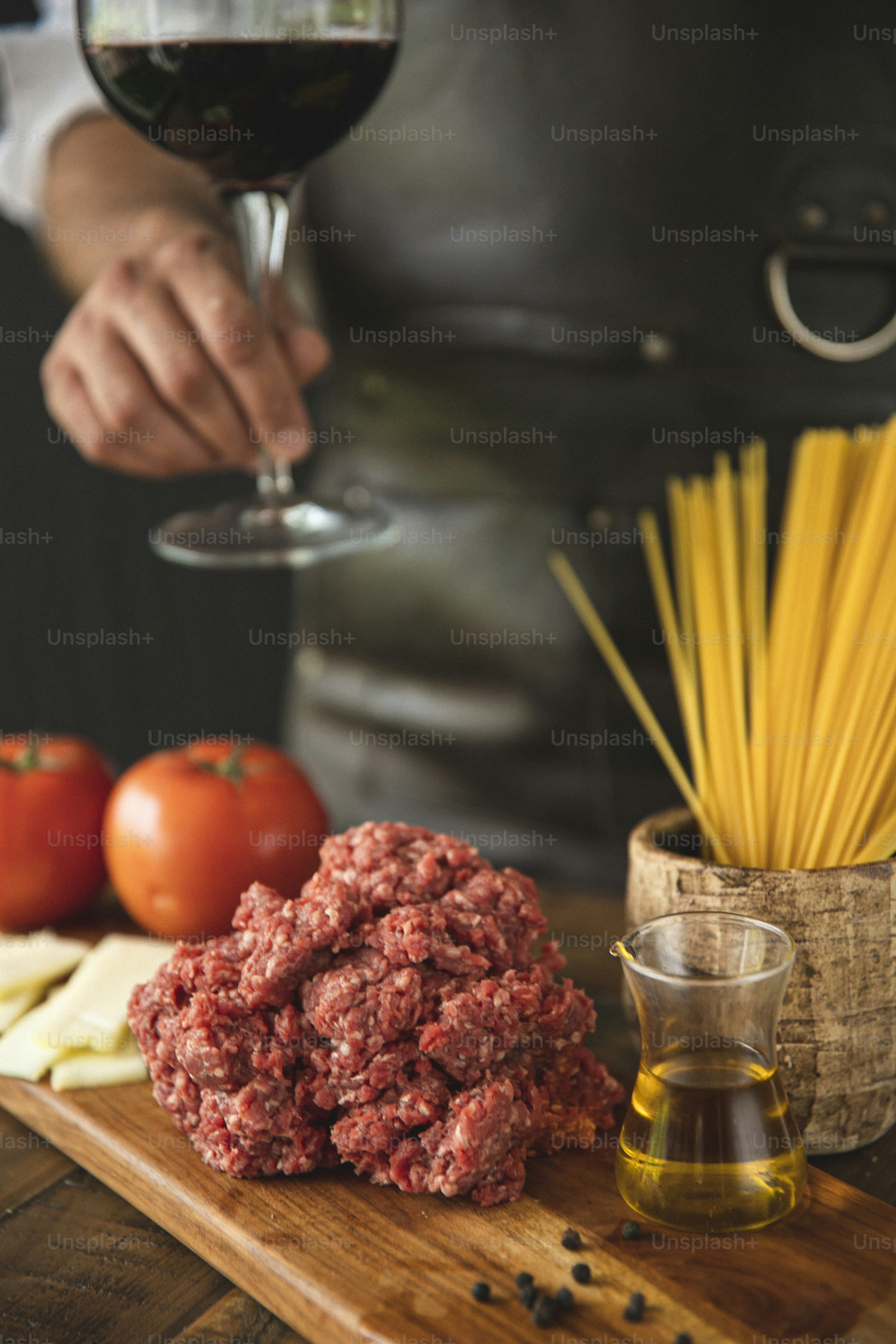 食べ物の皿の隣のグラスにワインを注ぐ人