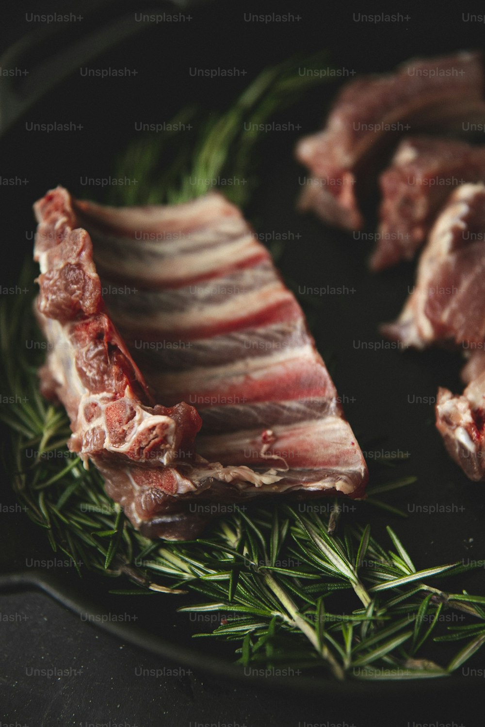 a plate of meat with rosemary on the side