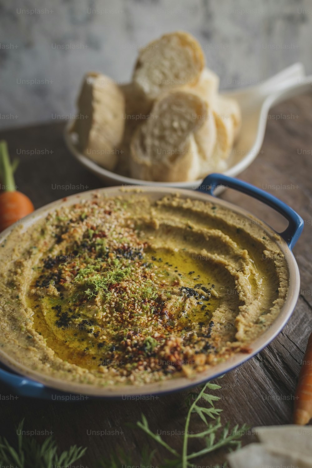 a bowl of hummus and carrots on a table