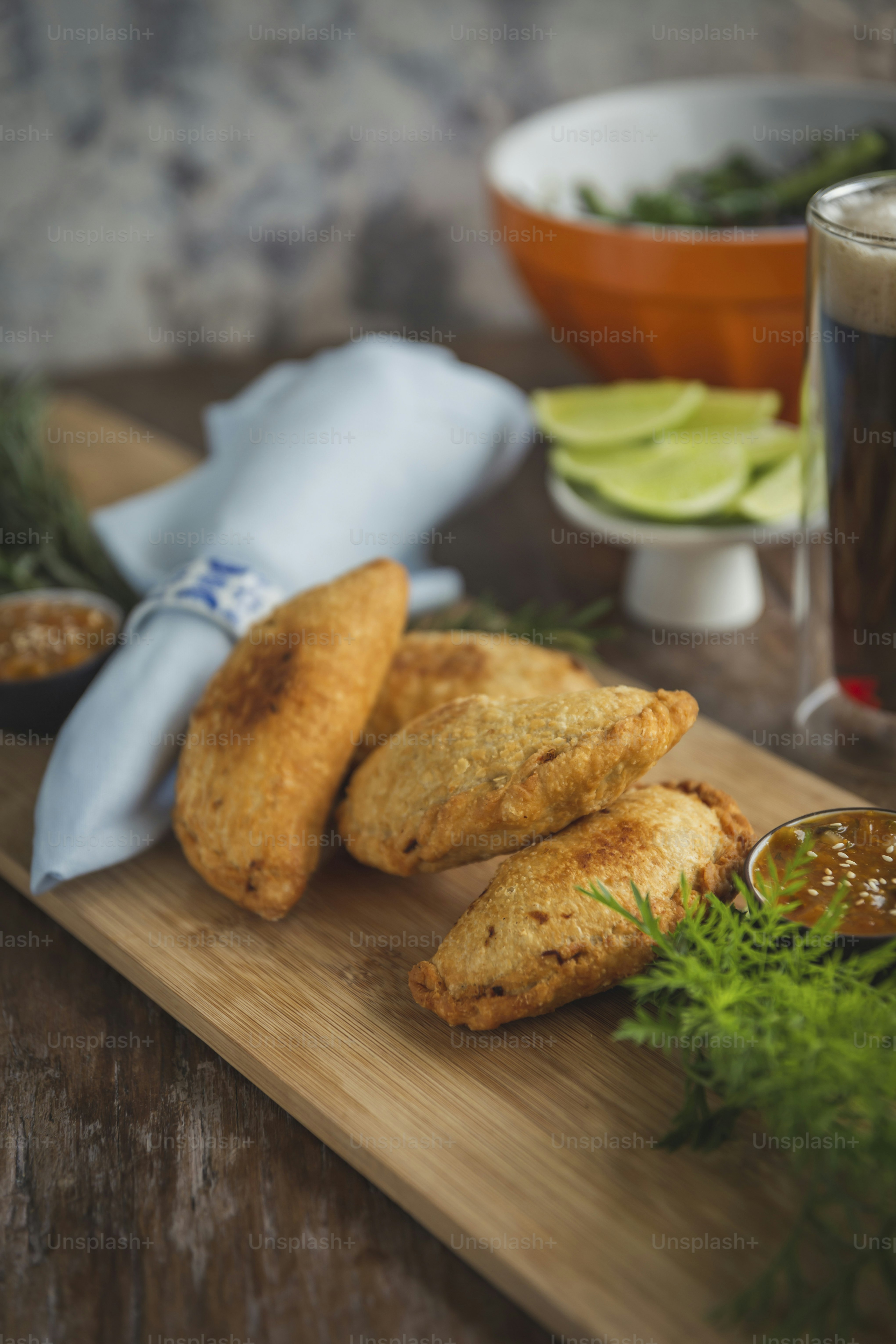 una tabla de cortar de madera cubierta con comida junto a un vaso de cerveza