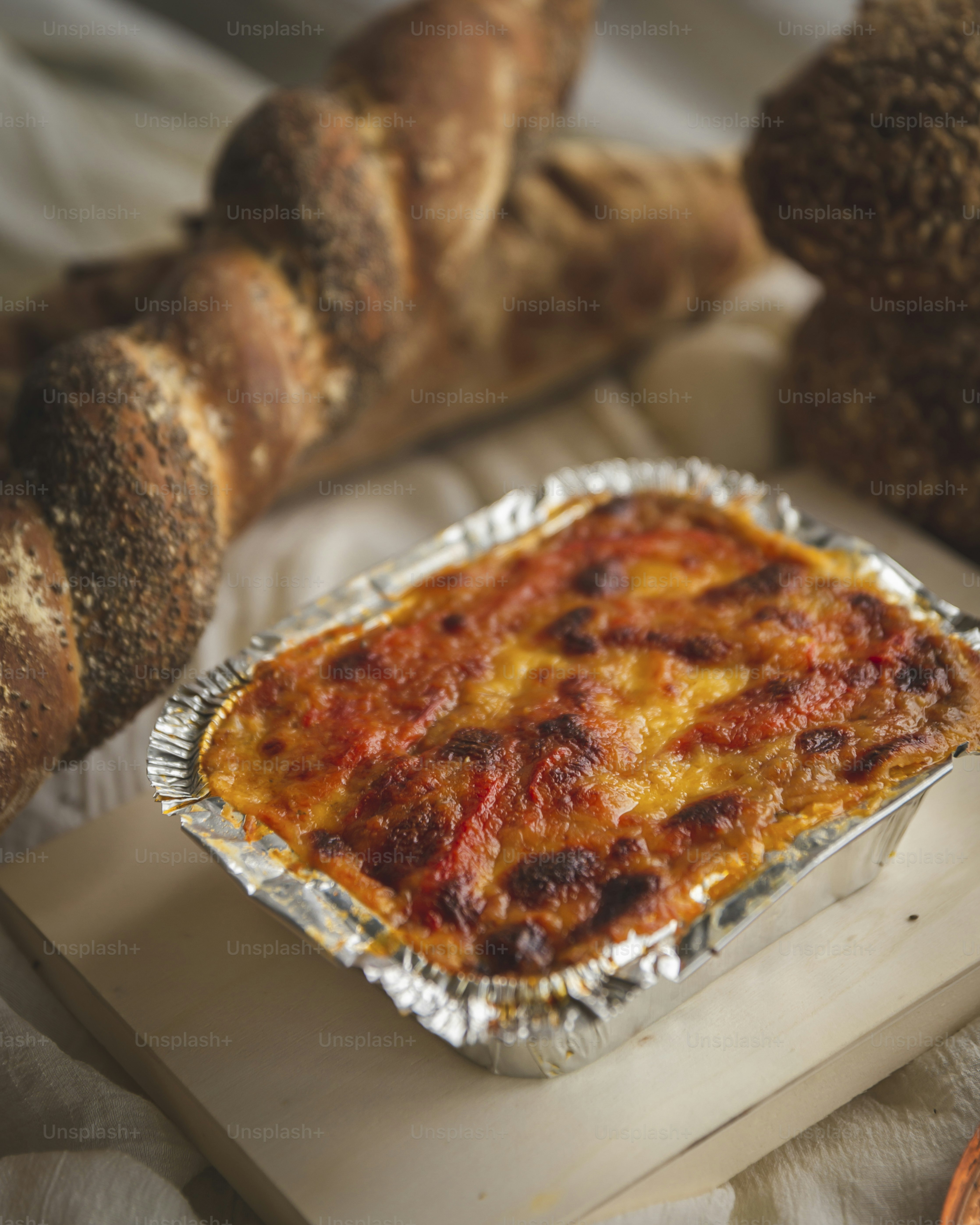 eine Auflaufform mit Käse und Brot im Hintergrund