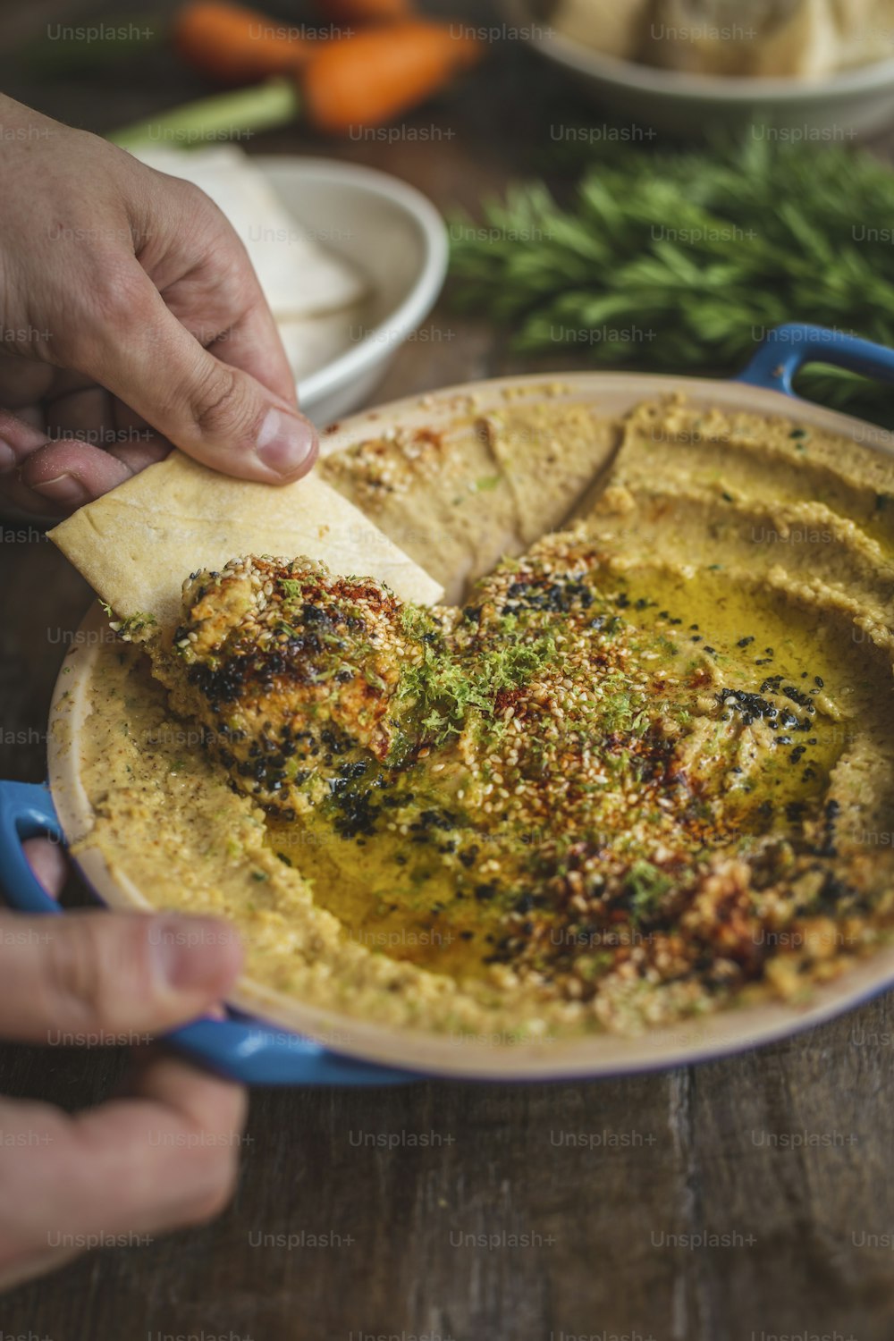 a person dipping a tortilla into a bowl of hummus