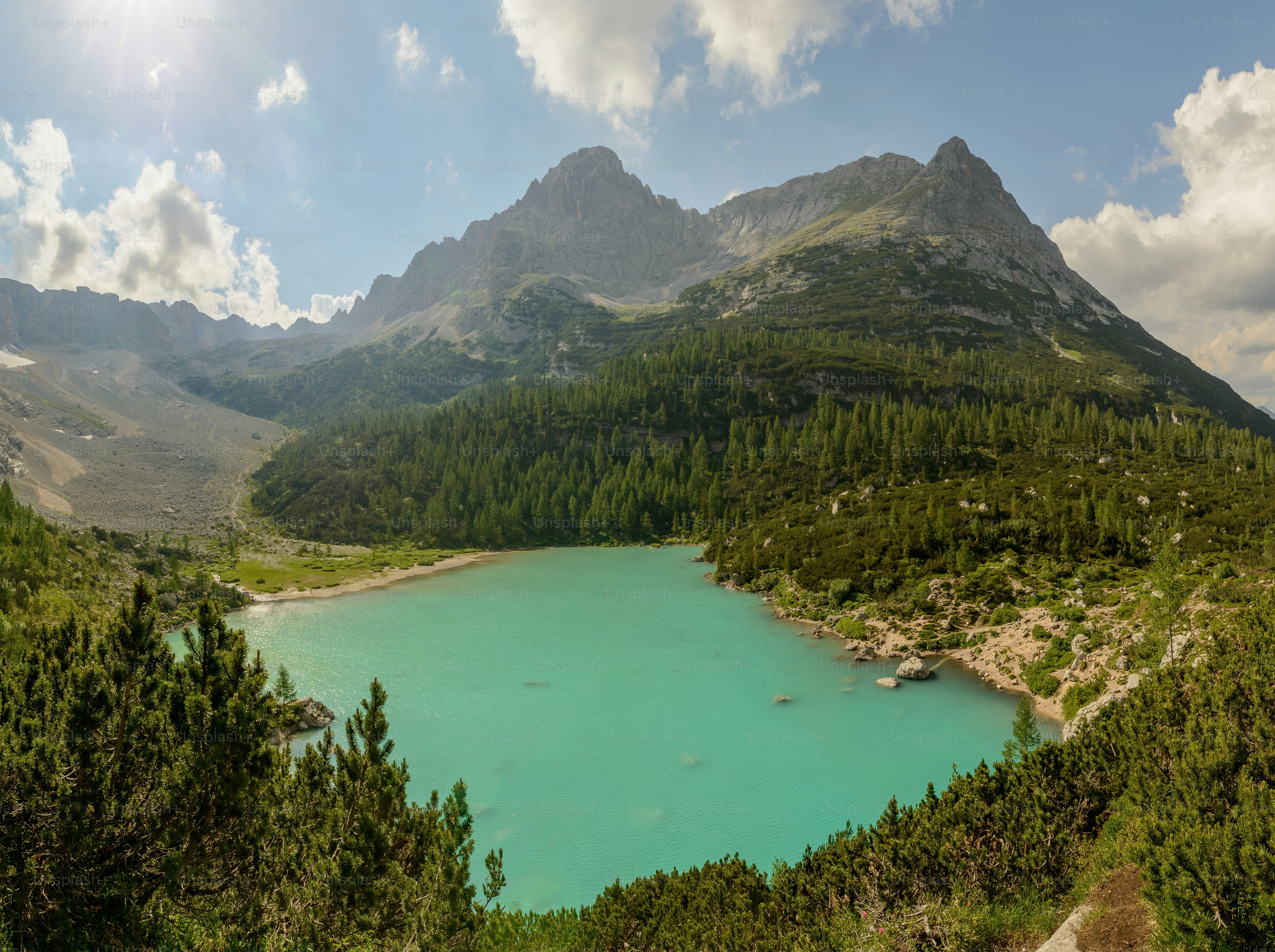 a lake surrounded by trees and mountains under a cloudy sky