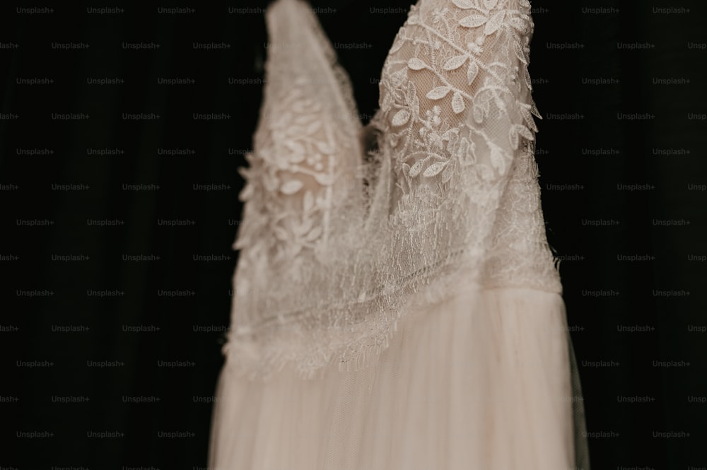 a wedding dress hanging on a black background