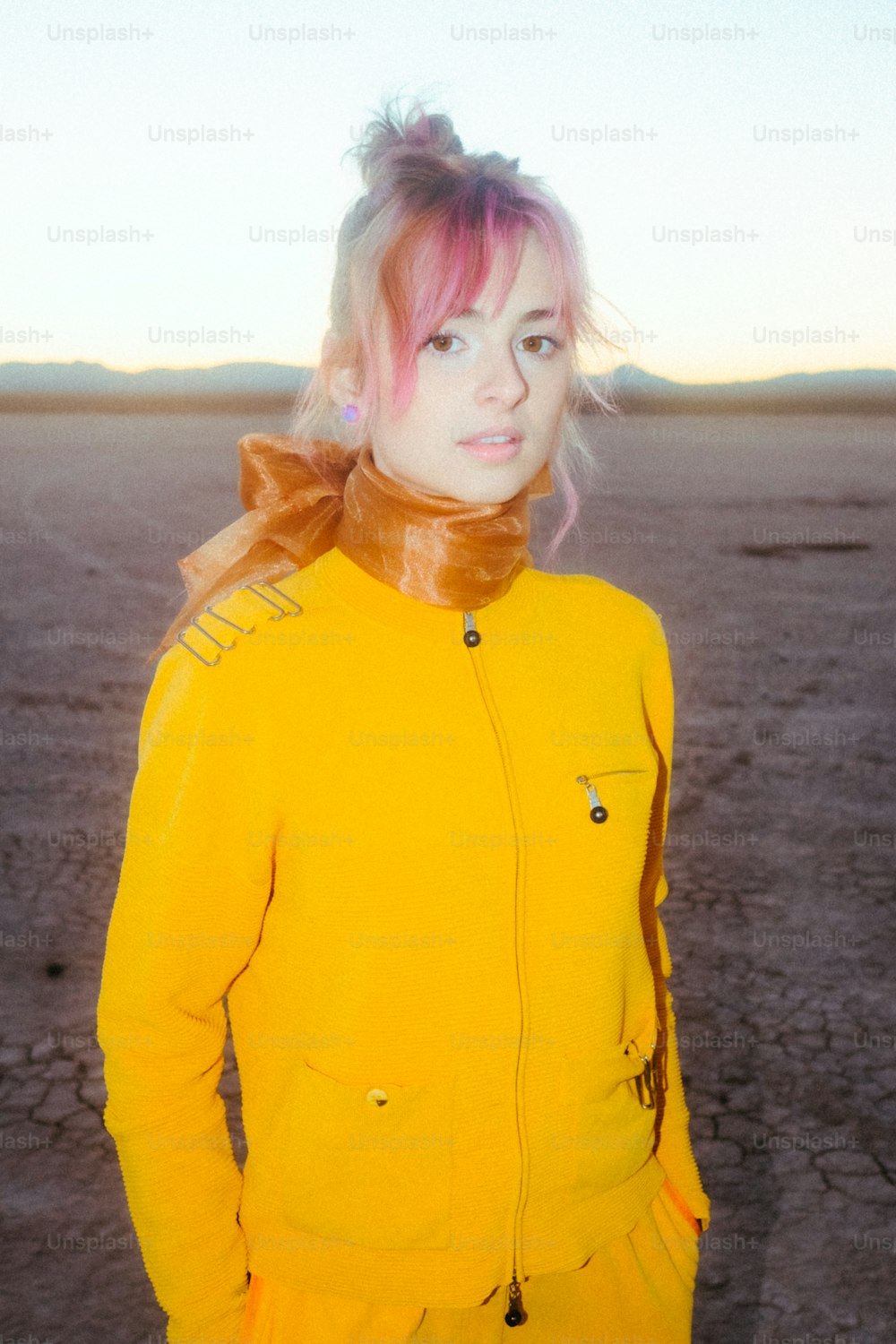 Una mujer con cabello rosa con una chaqueta amarilla