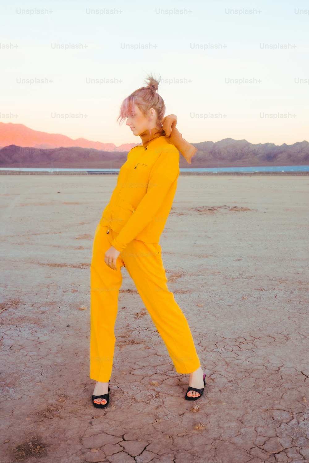 a woman in a yellow jumpsuit standing in the desert