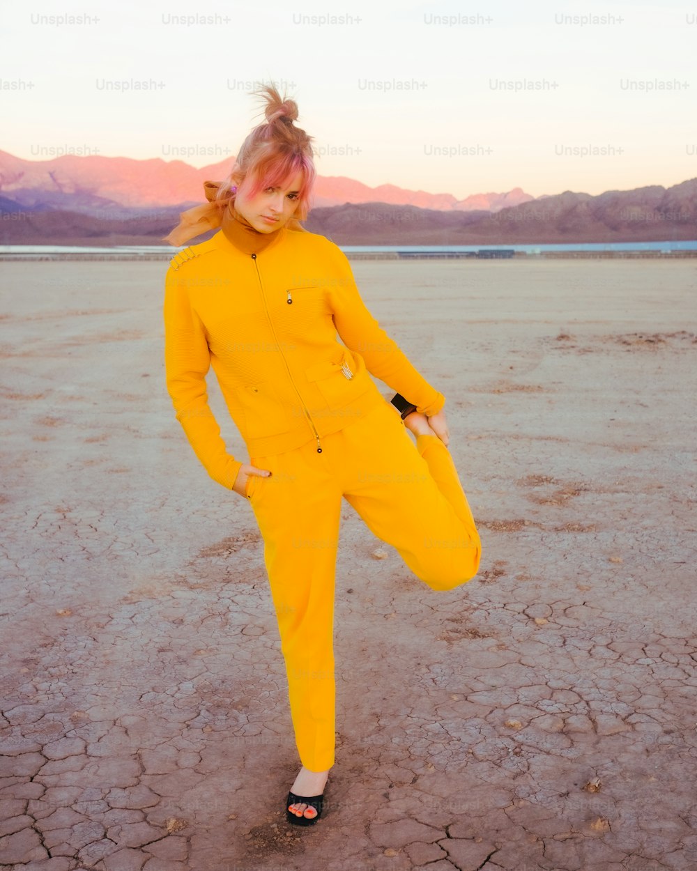 a woman in a yellow suit standing in a desert