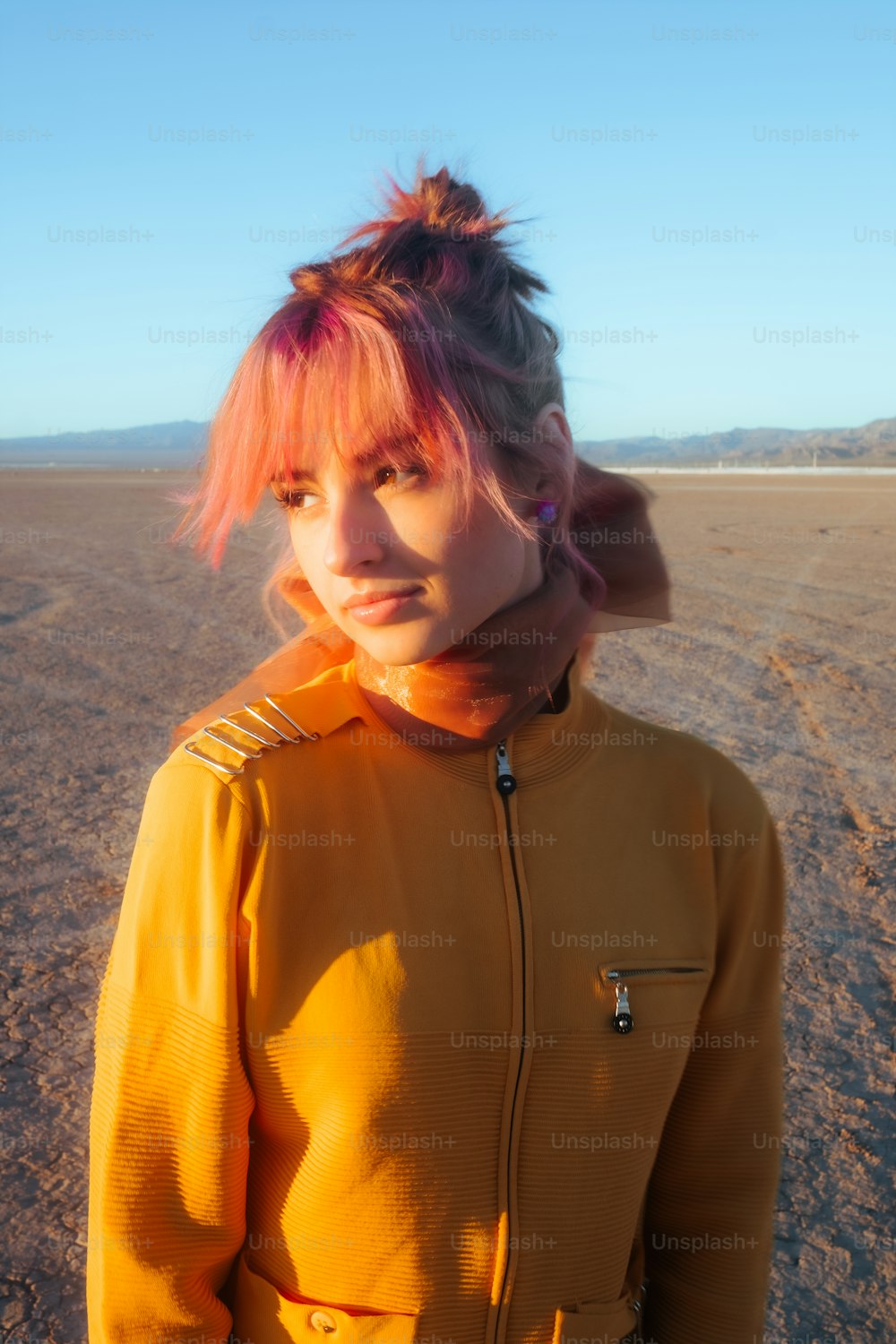 a woman with pink hair standing in the desert