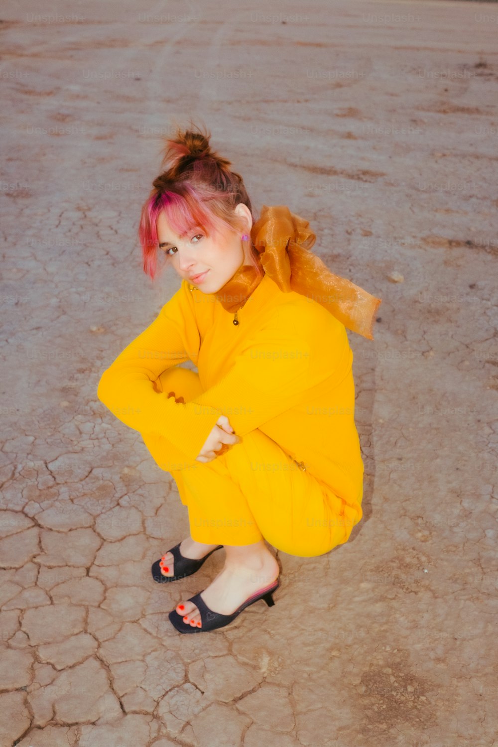 une femme en robe jaune assise par terre